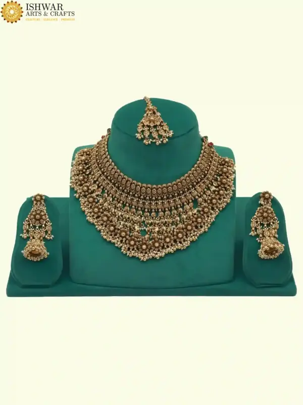 Antique gold intricate carving bridal necklace set with matching heavy earrings and maang tikka displayed on green jewelry stand, Ishwar Arts and Crafts