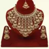 Antique gold bridal necklace set with hanging beads, matching jhumka earrings, and maangtika on red display stand, Ishwar Arts and Crafts