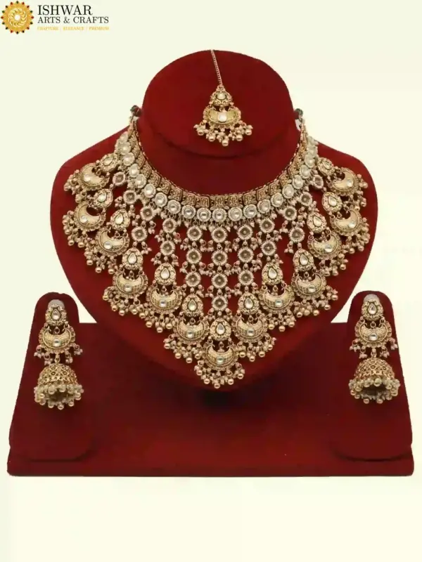 Antique gold bridal necklace set with hanging beads, matching jhumka earrings, and maangtika on red display stand, Ishwar Arts and Crafts