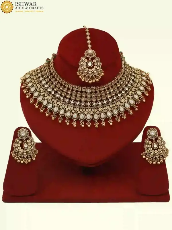 Antique gold brass bridal necklace set with Kundan stones, matching earrings, and maangtika on red display, Ishwar Arts and Crafts