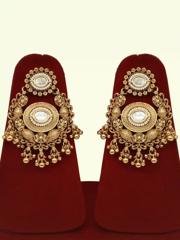 Heavy matte gold brass bridal necklace set with kundan stones, earrings, and maang tikka displayed on red jewelry stand, Ishwar Arts and Crafts