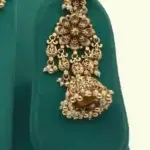 Antique gold intricate carving bridal necklace set with matching heavy earrings and maang tikka displayed on green jewelry stand, Ishwar Arts and Crafts