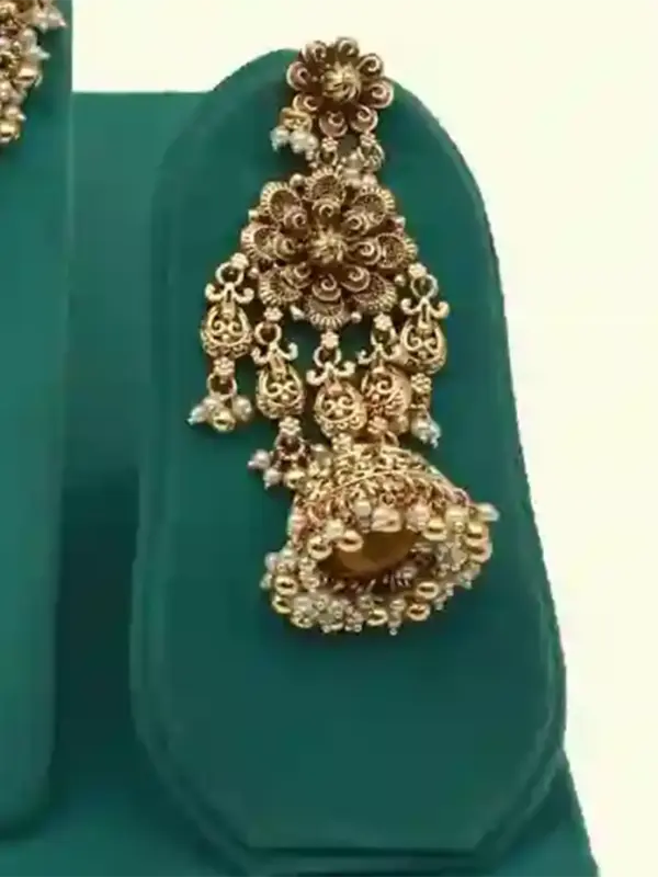 Antique gold intricate carving bridal necklace set with matching heavy earrings and maang tikka displayed on green jewelry stand, Ishwar Arts and Crafts