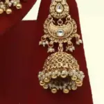 Antique gold bridal necklace set with hanging beads, matching jhumka earrings, and maangtika on red display stand, Ishwar Arts and Crafts