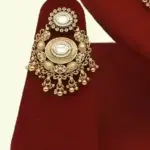 Heavy matte gold brass bridal necklace set with kundan stones, earrings, and maang tikka displayed on red jewelry stand, Ishwar Arts and Crafts