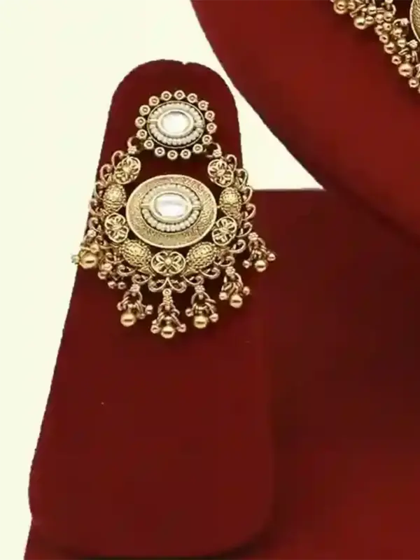 Heavy matte gold brass bridal necklace set with kundan stones, earrings, and maang tikka displayed on red jewelry stand, Ishwar Arts and Crafts